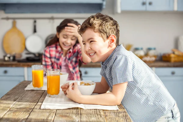 Glücklicher kleiner Junge frühstückt mit seiner Schwester — Stockfoto