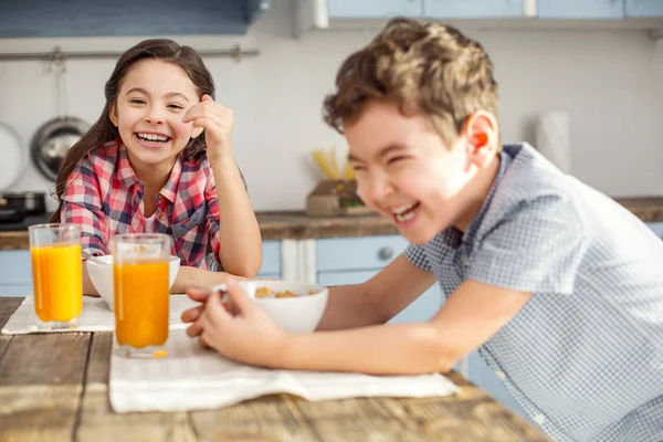 Fröhliche kleine Kinder lachen am Tisch — Stockfoto
