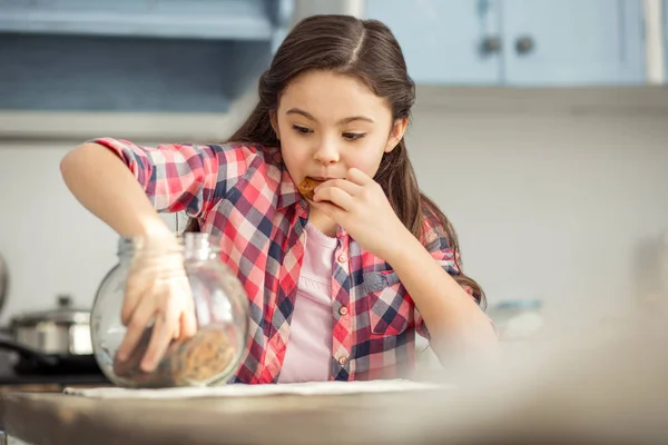 Радостная маленькая девочка ест печенье — стоковое фото