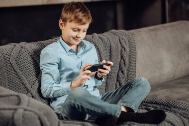 Kanepede oturan ve telefonda oynamak hoş çocuk