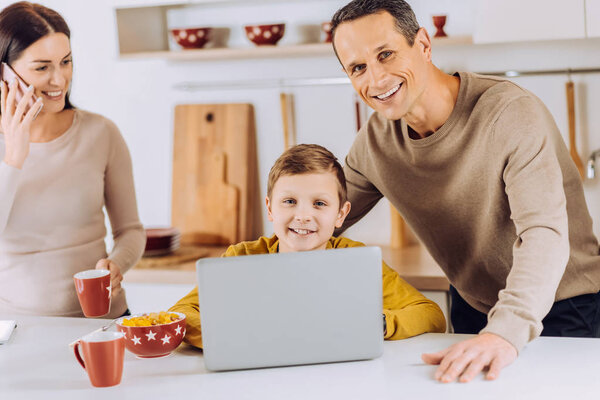 Pleasant man checking his sons work and posing with him