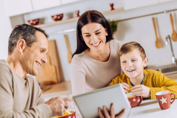 Upbeat father showing tablet to his family during breakfast
