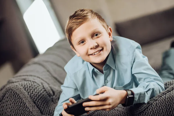 Lindo niño pre-adolescente acostado en el sofá y jugando juegos — Foto de Stock