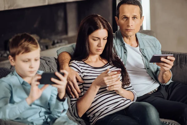 Joven y su familia pegados a sus teléfonos — Foto de Stock