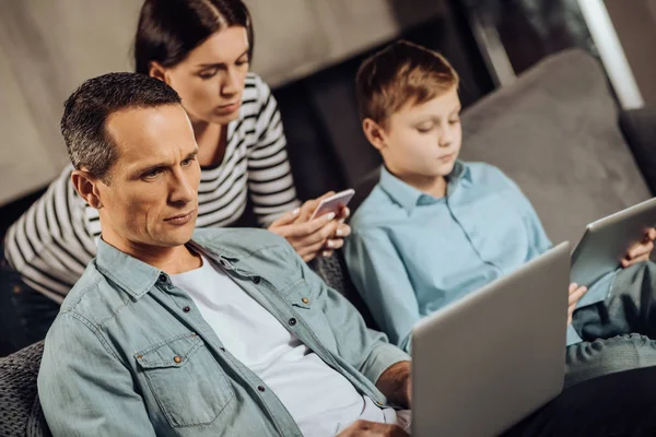 Joven familia teniendo su atención en sus aparatos — Foto de Stock