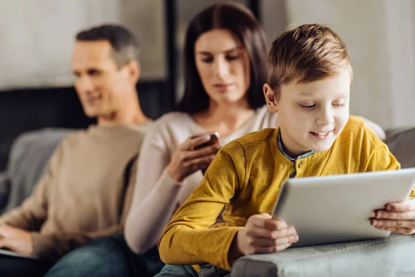 Pequeño niño jugando en la tableta mientras sus padres están ocupados — Foto de Stock