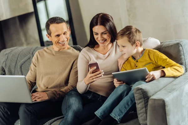 Upbeat woman showing something funny on phone to her family — Stock Photo, Image