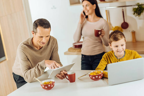Young family using their gadgets instead of having breakfast