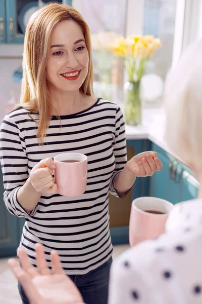 Piacevole donna che beve caffè con madre in cucina — Foto Stock