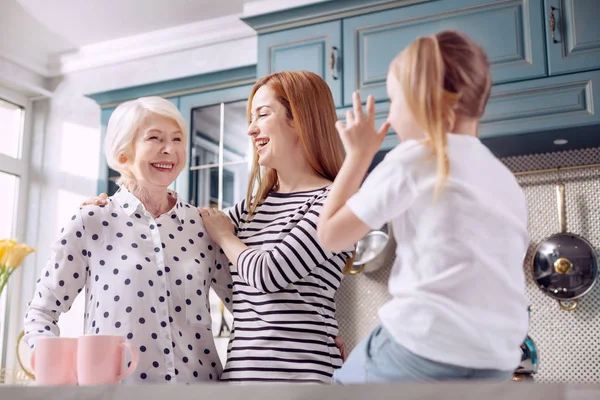 Nettes Mädchen im Gespräch mit ihrer Mutter und Großmutter in der Küche — Stockfoto