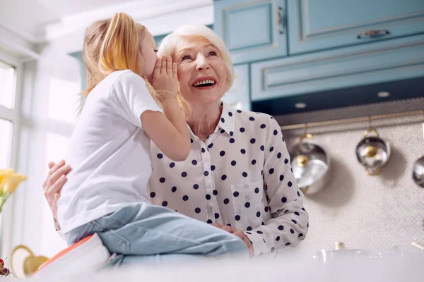 Glückliche Großmutter hört auf das Geheimnis ihrer Enkelinnen — Stockfoto