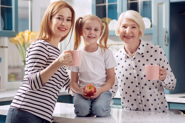 Meisje poseren in keuken met haar moeder en grootmoeder — Stockfoto