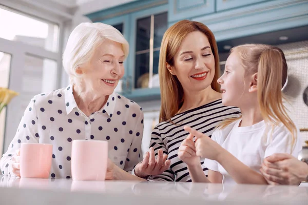 Cute girl telling funny story to her mother and grandmother — Stock Photo, Image