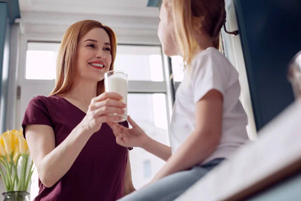 Kleines Mädchen nimmt Mutter ein Glas Milch aus der Hand — Stockfoto