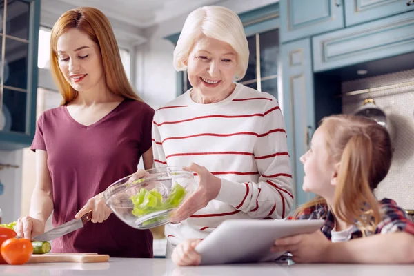 Маленька дівчинка показує рецепт салату мамі та бабусі — стокове фото