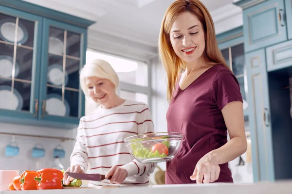 Ung kvinna och hennes mor att göra sallad tillsammans — Stockfoto