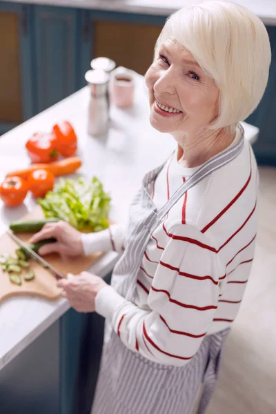 Fröhliche Seniorin posiert beim Salatbacken — Stockfoto