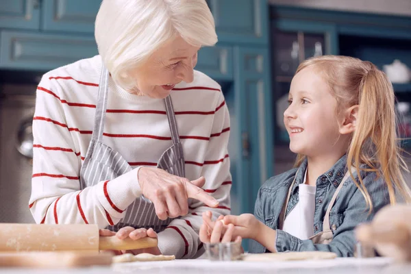 Przyjemna Kobieta wskazując na plik cookie w jej rękach wnuczki — Zdjęcie stockowe