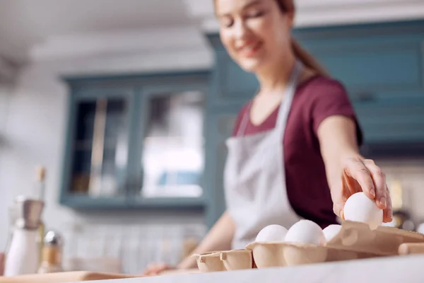 Pleasant young woman taking egg from egg carton — Stock Photo, Image