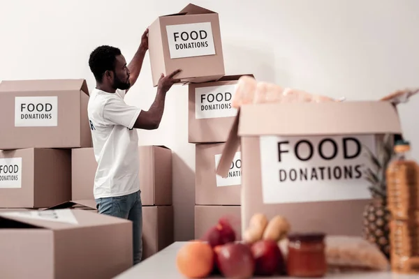 Voluntario serio recogiendo paquetes con comida — Foto de Stock