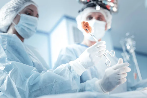 Responsible worried medics doing the operation looking at a clamp. — Stock Photo, Image