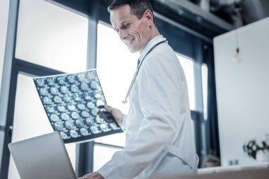 X-ray tarama tutarak ve gülümseyen neşeli perspektif doktor.