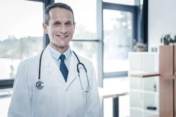 Médico confiante qualificado sentindo-se bem e sorrindo . — Fotografia de Stock