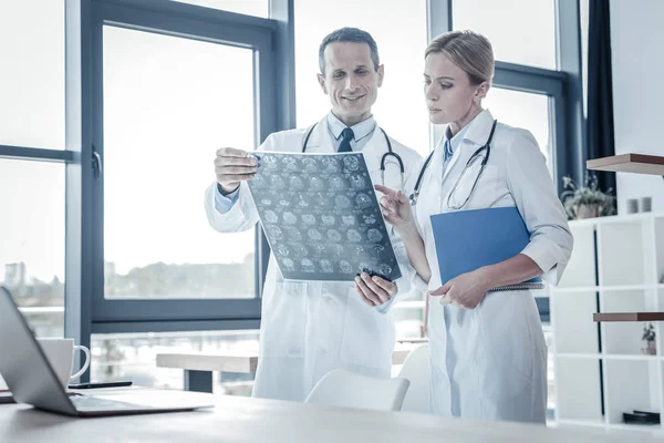 Qualifizierte selbstbewusste Mediziner stehen und untersuchen Röntgenbilder. — Stockfoto