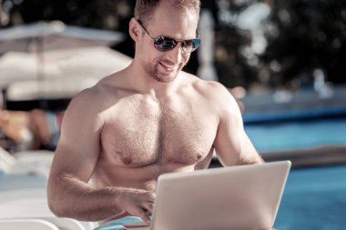 Dizüstü bilgisayar açık havada kullanırken gülen serin genç adam