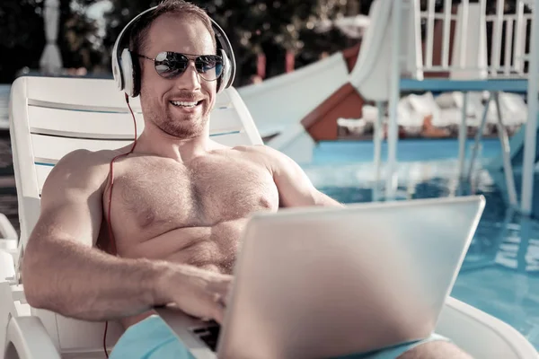 Male entrepreneur grinning broadly while working at swimming pool