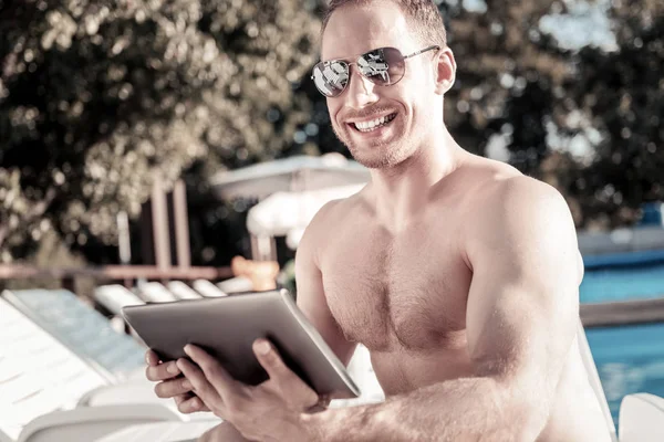 Well built young man with touchpad grinning broadly outdoors — Stock Photo, Image