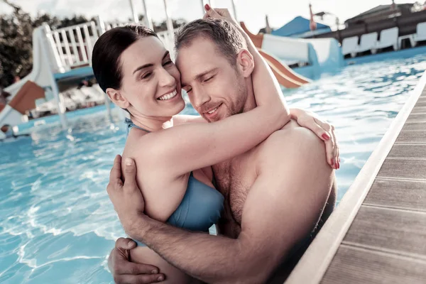 Adorable millennial couple hugging and smiling in swimming pool — Stock Photo, Image