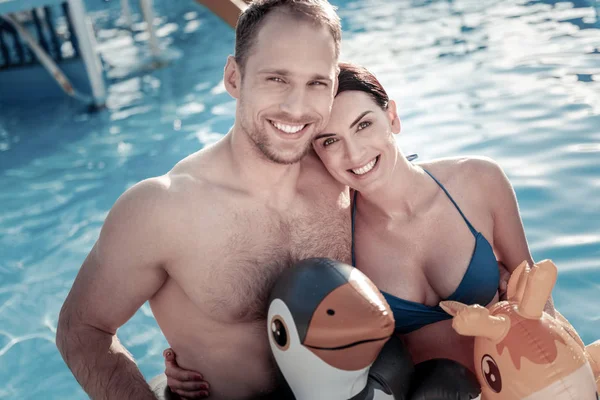 Embracing millennial couple smiling into camera while swimming — Stock Photo, Image