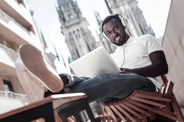 Självsäker tusenåriga killen tittar in i kameran medan du arbetar på laptop — Stockfoto