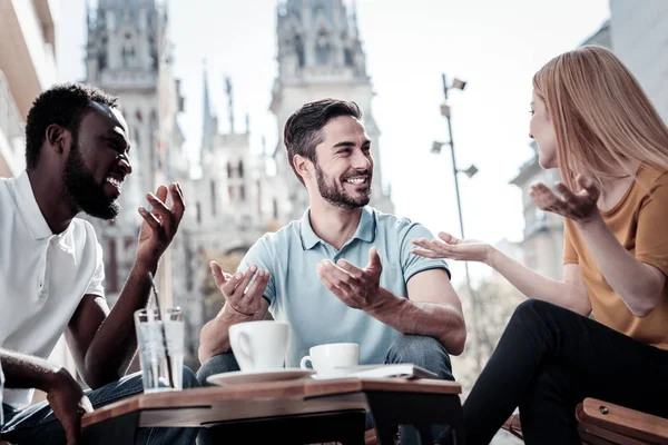 Amigos extremadamente felices haciendo gestos y sonriendo mientras toman — Foto de Stock