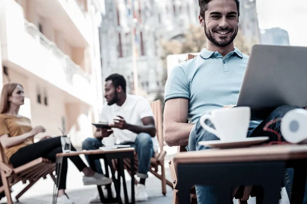 Vrolijke jonge man die lacht tijdens het werken op de laptop — Stockfoto