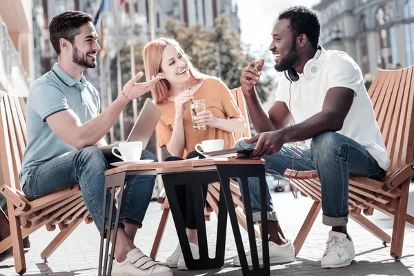 Milenial amigos sonriendo mientras se reúnen en la cafetería — Foto de Stock