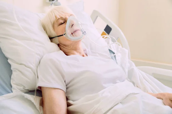 Starší žena s kyslíkovou maskou ležela v nemocniční posteli — Stock fotografie