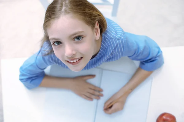 Leuk meisje met grote ogen zitten en glimlachen — Stockfoto