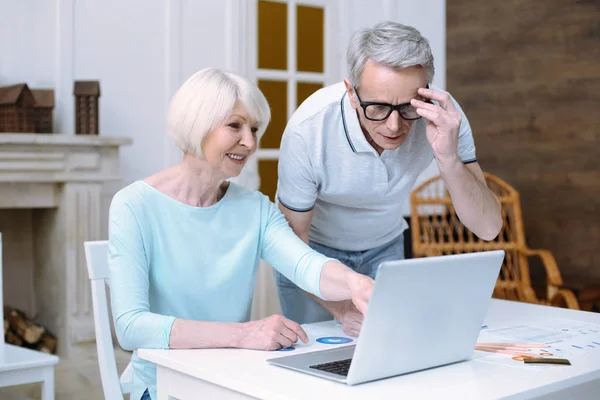 Velho casal positivo olhando para a tela de um laptop — Fotografia de Stock