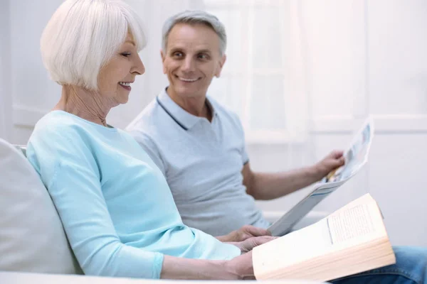 Amistosa pareja de ancianos compartiendo noticias y sonriendo — Foto de Stock