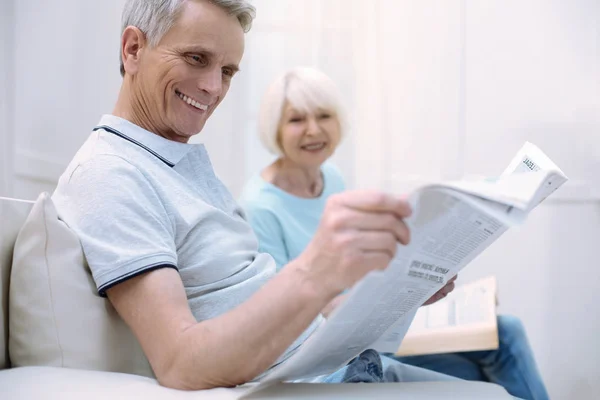 Старший смеется, читая газету — стоковое фото