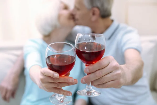 Lindos ancianos sosteniendo bebidas y besándose — Foto de Stock