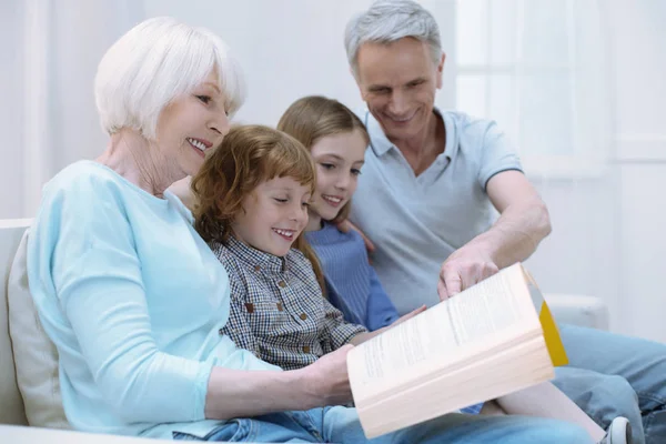 Cuatro parientes cercanos sentados juntos y leyendo — Foto de Stock