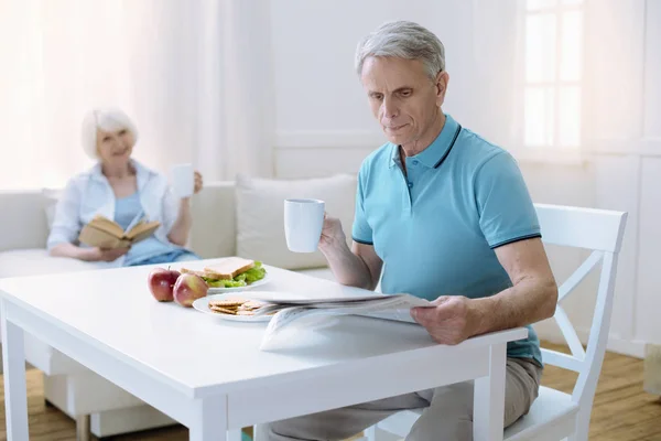 Serious pensioner reading his interesting newspaper — Stock Photo, Image