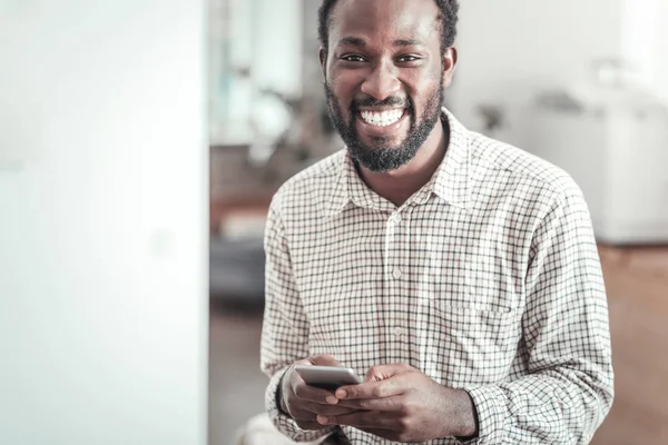 Feliz hombre agradable sosteniendo su teléfono inteligente — Foto de Stock