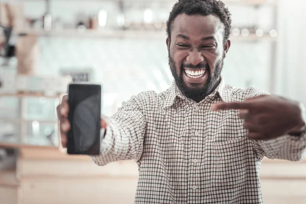 Feliz buen hombre apuntando al teléfono inteligente — Foto de Stock