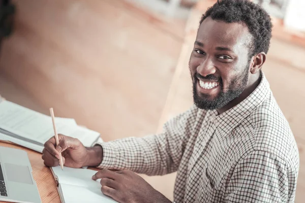 Gioioso uomo bello che fa il suo compito a casa — Foto Stock