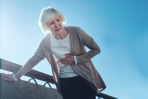 Frightened senior woman having heart attack outdoors — Stock Photo, Image