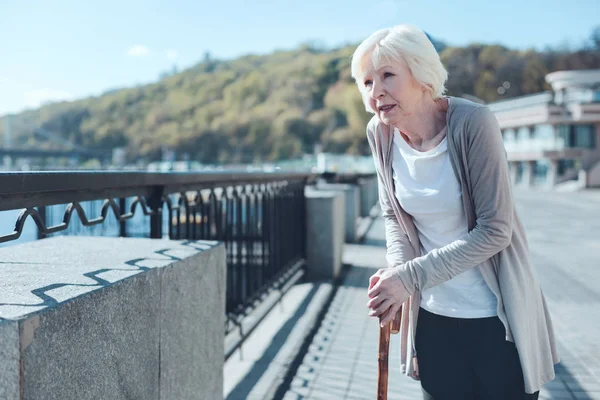 Sjuka äldre dam promenading längs flodpromenaden — Stockfoto